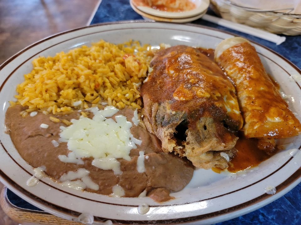 A tray of tacos beside rice and beans.